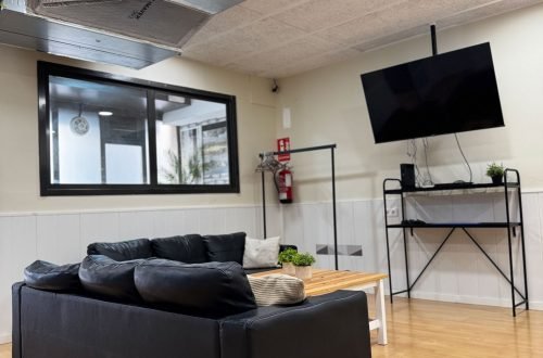 Interior del local L’Ambient con zona de sofás y equipo multimedia para celebraciones.