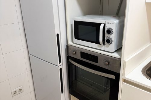 Cocina equipada con nevera, microondas y horno en sala de alquiler para fiestas y celebraciones en Gavà