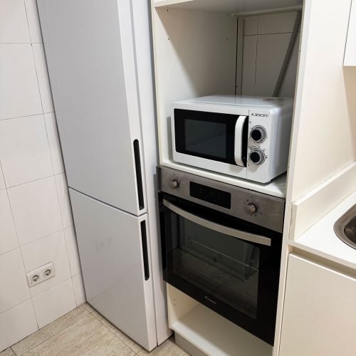 Cocina equipada con nevera, microondas y horno en sala de alquiler para fiestas y celebraciones en Gavà