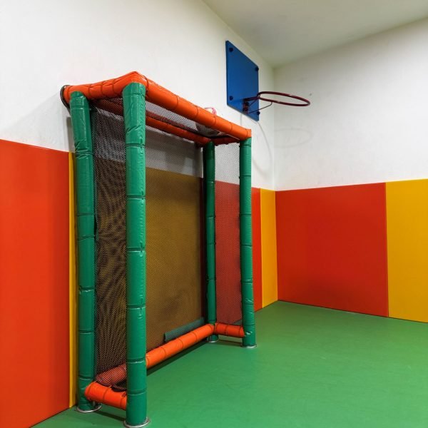 Zona de juegos infantil en sala para cumpleaños en Gavà con portería acolchada y canasta de baloncesto en local de fiestas infantiles.