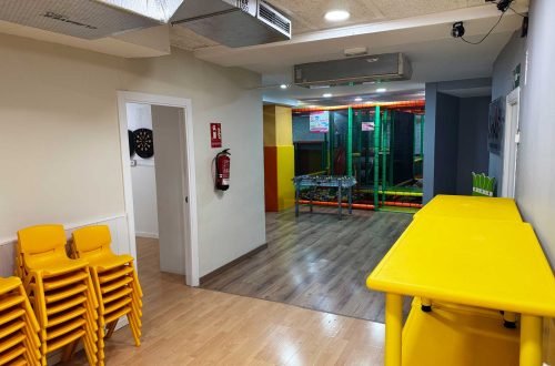 Interior del local L’Ambient en Gavà con mesas, sillas apiladas y acceso a la zona de juegos para cumpleaños y fiestas infantiles.