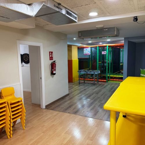 Interior del local L’Ambient en Gavà con mesas, sillas apiladas y acceso a la zona de juegos para cumpleaños y fiestas infantiles.